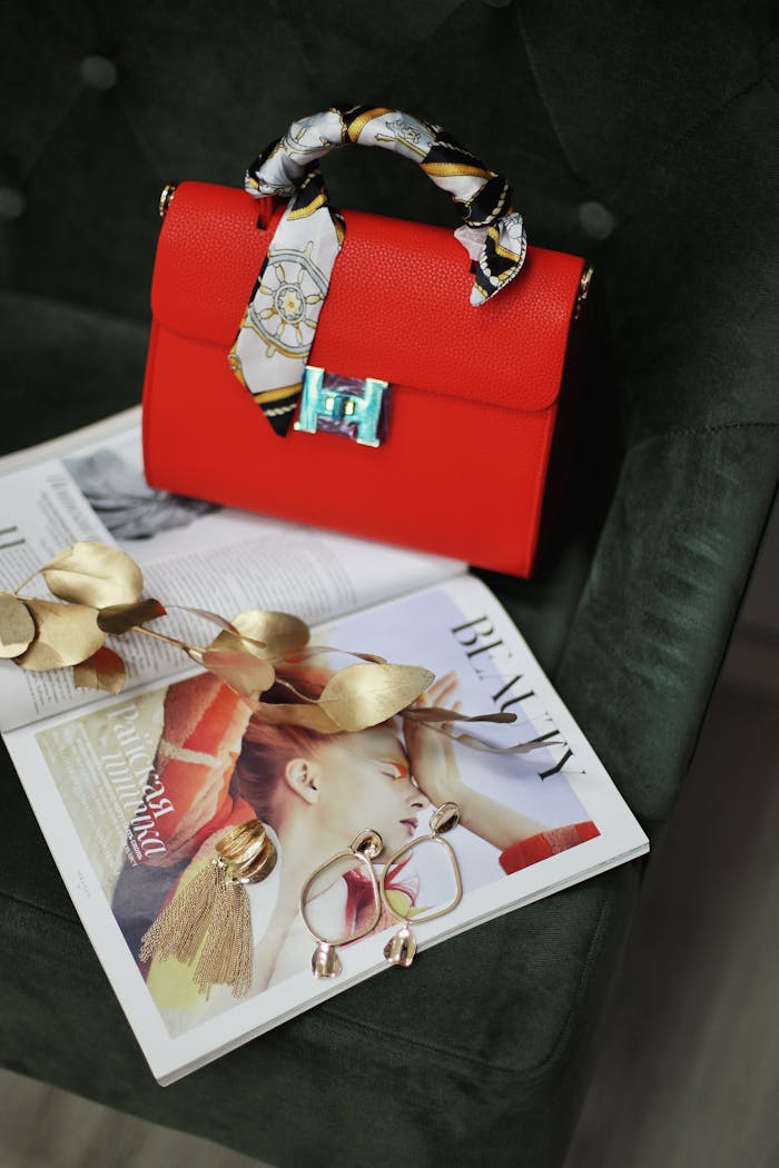 Stylish red handbag with golden accents atop a fashion magazine, ideal for a modern fashion backdrop.